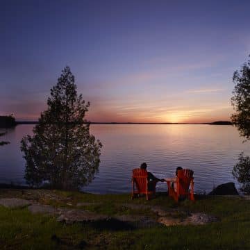 Taboo - couple in muskoka chairs at sunset looking over Lake Muskoka