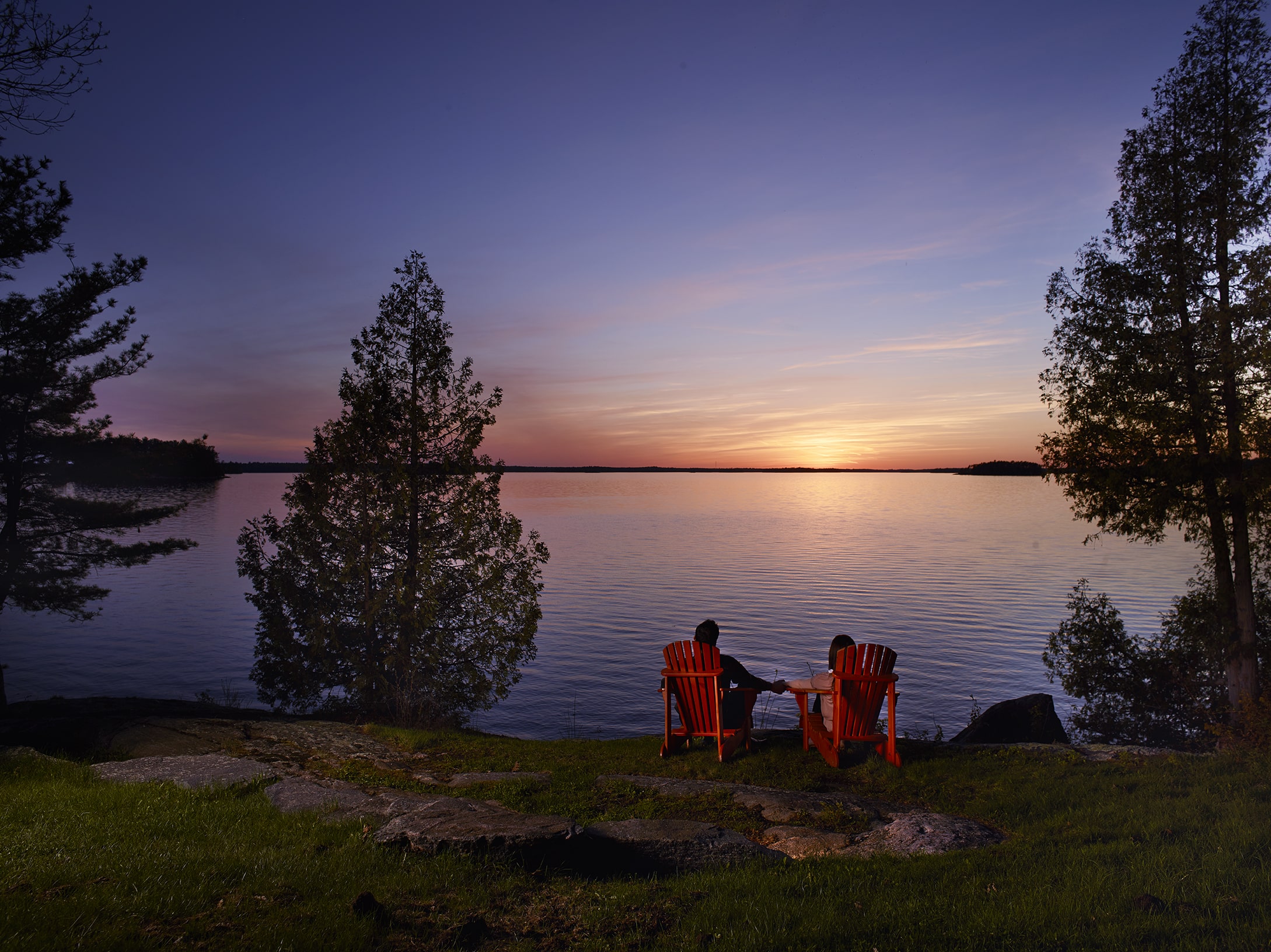Taboo - couple in muskoka chairs at sunset looking over Lake Muskoka