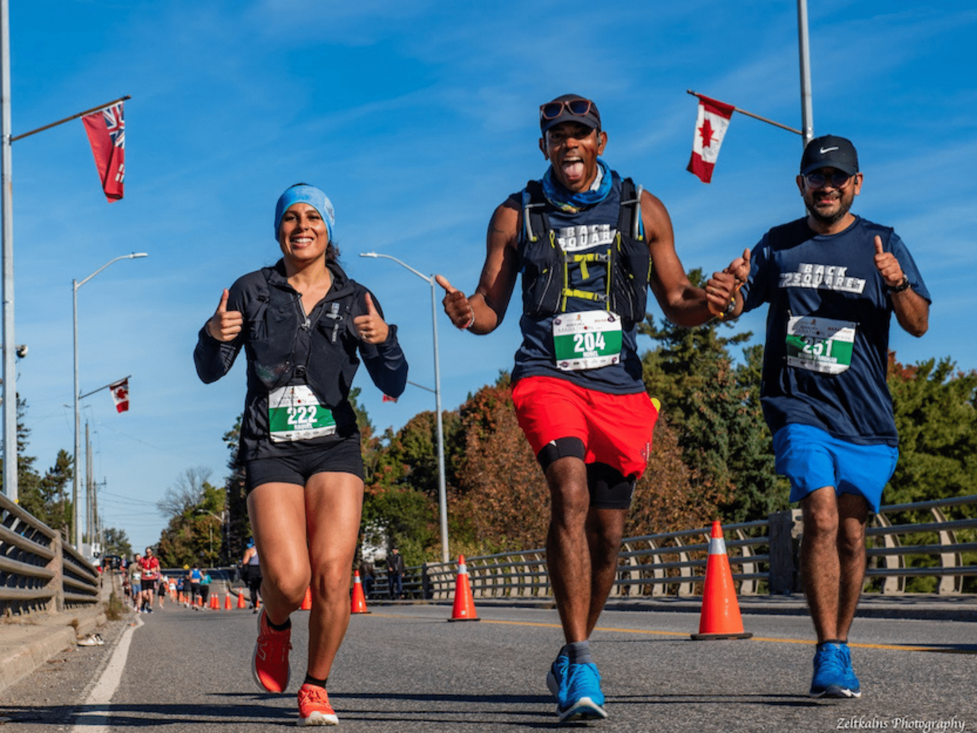 three road race runners giving thumbs up during middle of the muskoka marathon